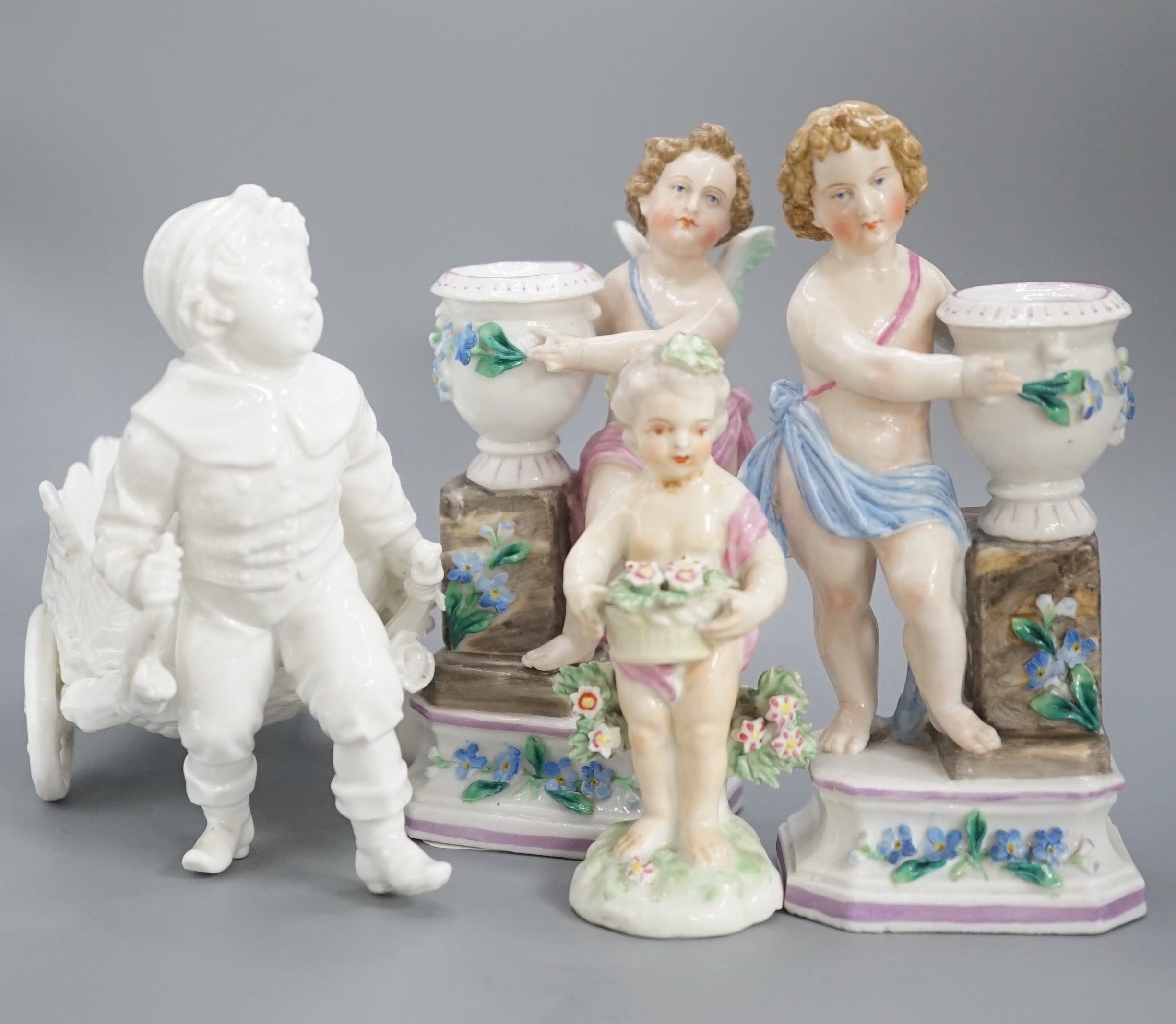 A pair of Continental porcelain cherub candlesticks, 13.5cm, a figural bonbon and a Derby figure